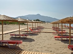 Соломенные зонтики и лежаки на песчаном пляже Закинфа
