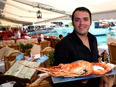 64_A-Greek-fish-taverna-waiter-showing-off-a-lobster-at-a-restaurant-in-Crete,-Greece